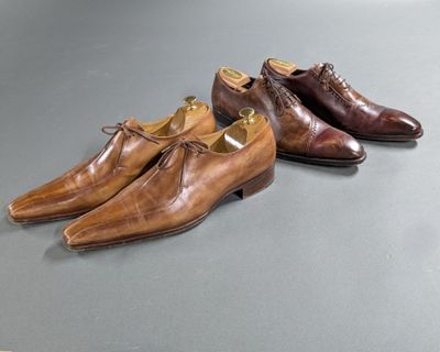 two pairs of brown shoes sitting on top of a table