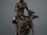 une statue en bronze représentant une femme tenant un enfant et un chien dans ses bras