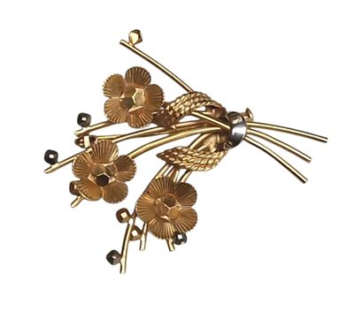 une image représentant une broche en forme de fleur en or, ornée de perles et de perles de verre