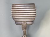 a small metal object on the wall next to a toothbrush