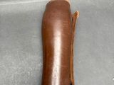 a hand holding a brown leather case on a table