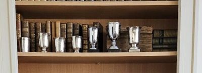 une bibliothèque remplie de trophées en argent et de livres