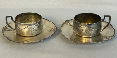 une paire de tasses et soucoupes plaquées argent posées sur un fond blanc