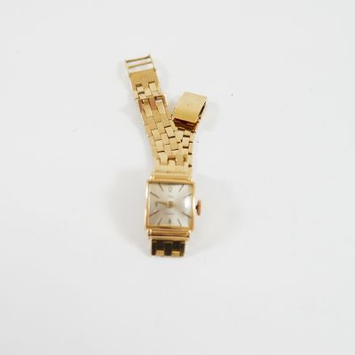 une image représentant une montre en or posée sur une surface blanche, sur fond blanc