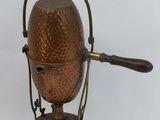 a small copper kettle on a stand with a wooden handle