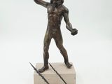 bronze statue of a man holding a spear and a bow