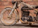 a old motorcycle that is sitting in front of a brick wall