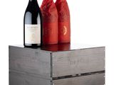 two bottles of wine sitting on top of a wooden crate