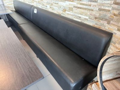 un banc en cuir noir devant un mur de briques