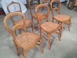 six chaises en bois disposées dans une pièce, avec un lit en arrière-plan