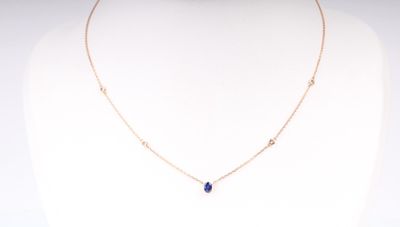 un collier en or orné d'une pierre bleue autour du cou d'un mannequin