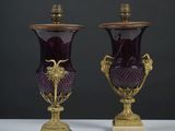 une paire de vases en verre violet rehaussés de touches dorées, posés sur une table blanche