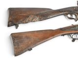 two old guns are on display on a white surface