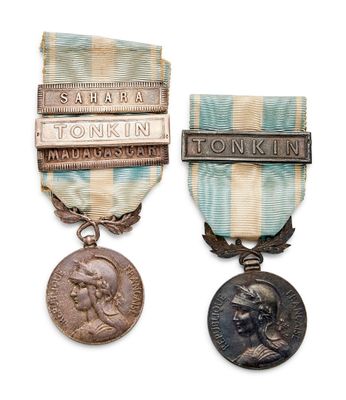 two medals are displayed on a white surface with a blue ribbon
