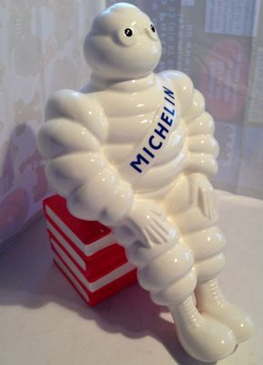 une statue blanche représentant un homme assis sur une boîte rouge