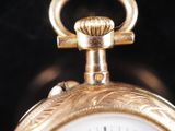 a close up of a gold pocket watch on a black background
