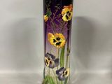 un vase avec des fleurs peintes dessus, posé sur une table