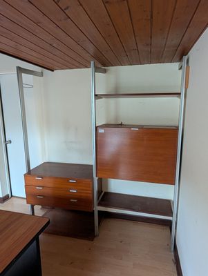 une photo d'une chambre avec un bureau et des étagères