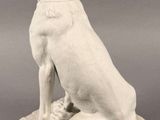 statue of a white dog sitting on a stone base