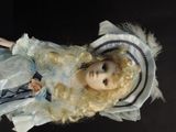 a doll with blonde hair wearing a blue dress and hat