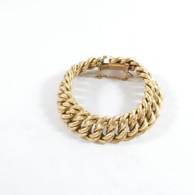 gros plan d'un bracelet en or sur une surface blanche