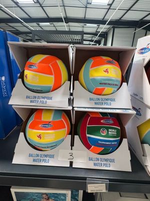 Des cartons de ballons de volley-ball sont empilés sur une table dans un magasin