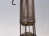 an old metal lantern with a light inside of it on a white surface