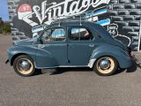 a small blue car parked in front of a vintage sign