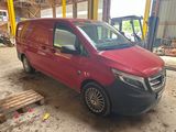 La camionnette rouge est garée dans le garage, la porte ouverte.