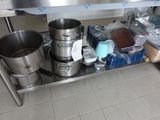 une table en acier inoxydable sur laquelle sont posés des casseroles et des poêles