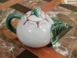 une théière décorée d'une grenouille, posée sur une table