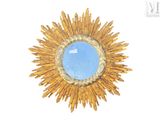 a blue stone in the center of a gold sunburst
