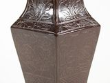 un vase marron posé sur une surface blanche
