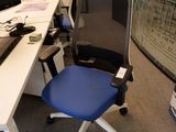 un bureau d'ordinateur avec une chaise bleue et un écran posé dessus