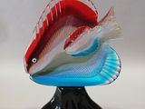 a red and white fish sitting on top of a black stand