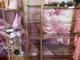 a gold shelf with pink flowers on it in the corner of a room