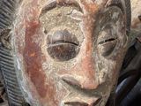 a wooden mask sitting on top of a pile of metal