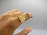 someone is holding a gold ring with a picture of a man ' s face on it