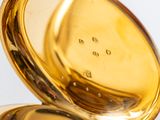 a close up of a gold pocket watch on a white surface