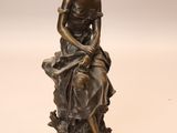 bronze statue of a woman sitting on a rock with a dog
