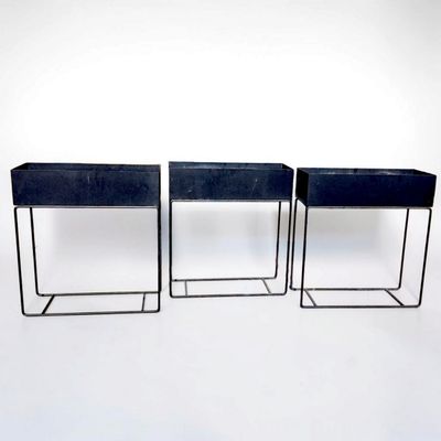 three black planters that are sitting on a white surface