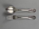 two silver spoons and a fork on a table