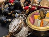 a small pocket watch sitting next to a bunch of rosary beads