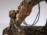 bronze statue of a horse and a child on a rock