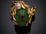 a close up of a gold ring with a green beetle and a pearl