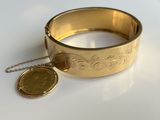 bracelet en or avec une pièce et une chaîne sur un fond blanc