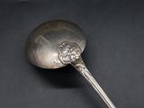 silver spoon on a black surface with a flower design on it