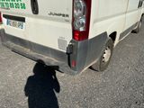 une camionnette blanche garée sur un parking, dont l'ombre se projette au sol