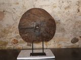 un grand objet en bois posé sur un socle devant un mur de pierre