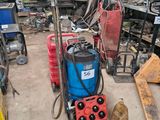 une machine bleue et rouge dans un garage, à côté d'autres outils